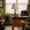 Female military psychologist in professional attire conducting therapy session with male service member in uniform in private counseling office
