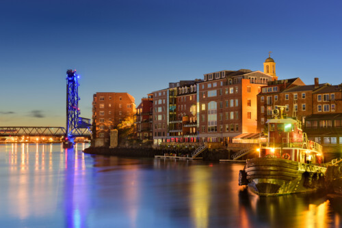 New Hampshire - Shutterstock | CareersinPsychology.org Portsmouth New Hampshire waterfront at sunset with Memorial Bridge and historic buildings representing communities where licensed social workers serve families and individuals